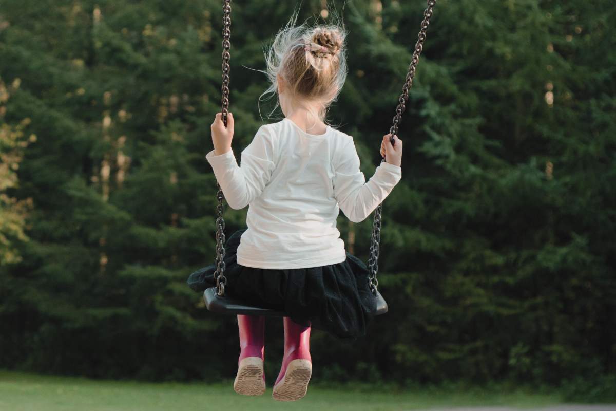 Bambina di spalle va sull'altalena