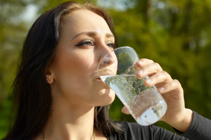 ragazza con cappelli lunghi che beve bicchiere acqua frizzante